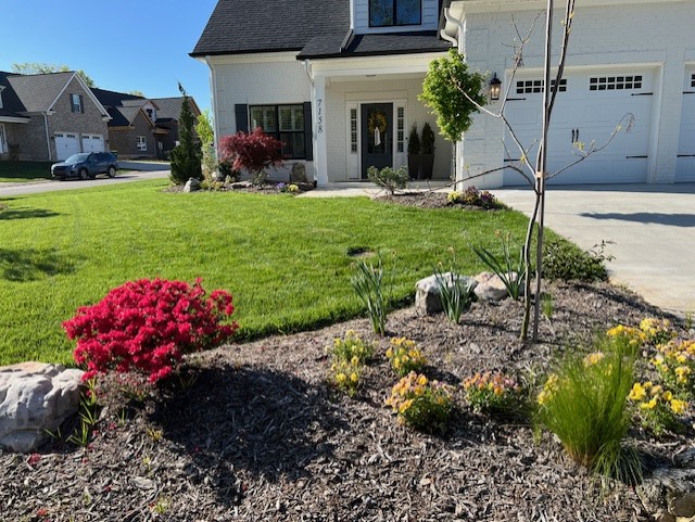 A beautiful white house with a luscious lawn and colorful flowers