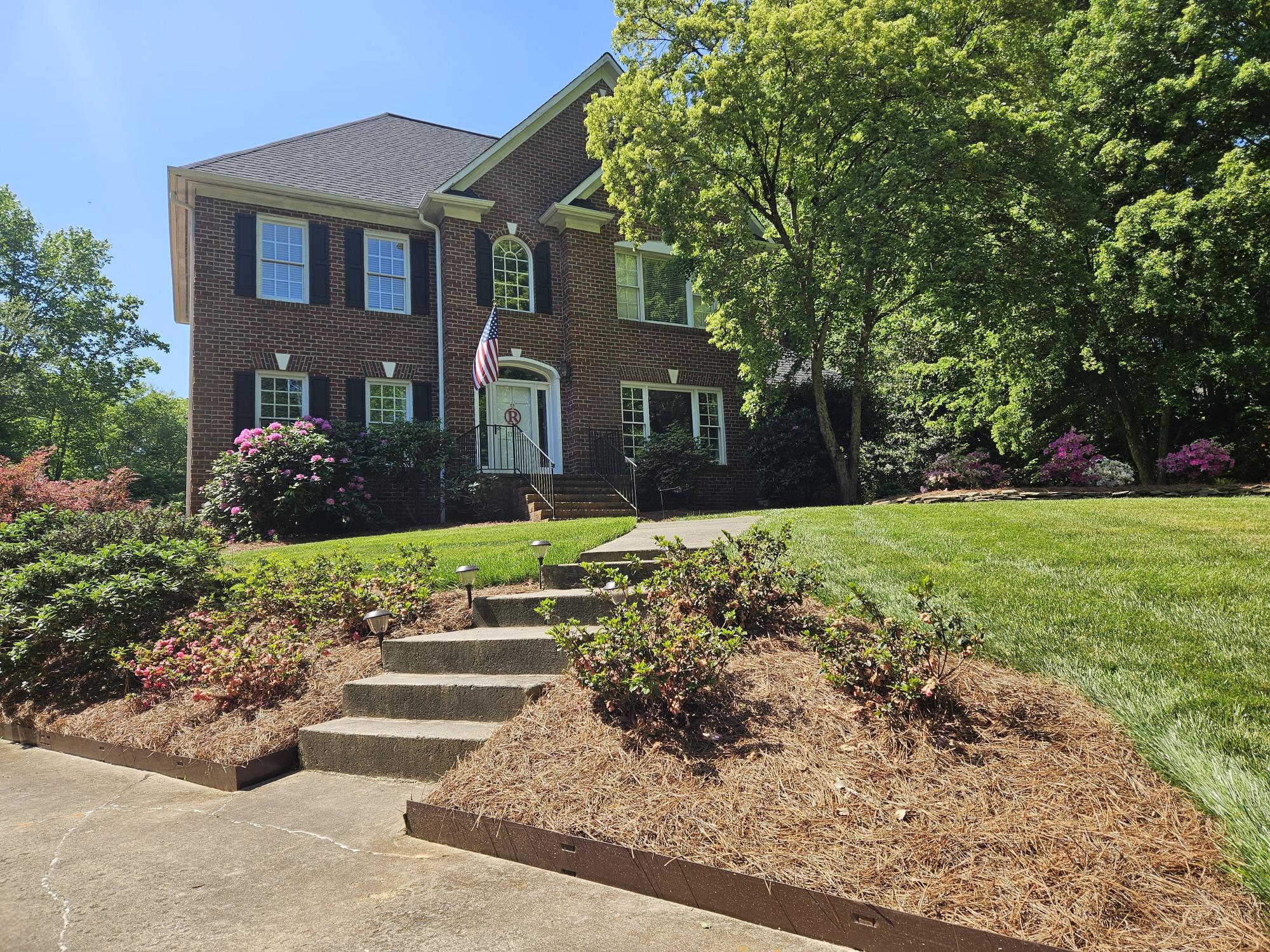 Landscaped steps lead up to a two story brick house