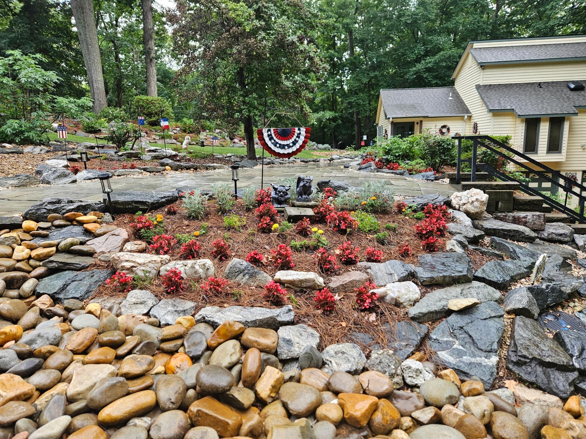 A stunning landscaping island has pine needles, beautiful rocks, and lights.
