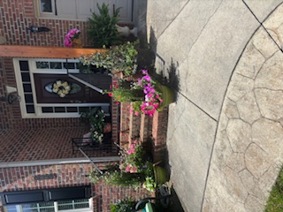 Colorful potted flowers line brick steps at a front porch