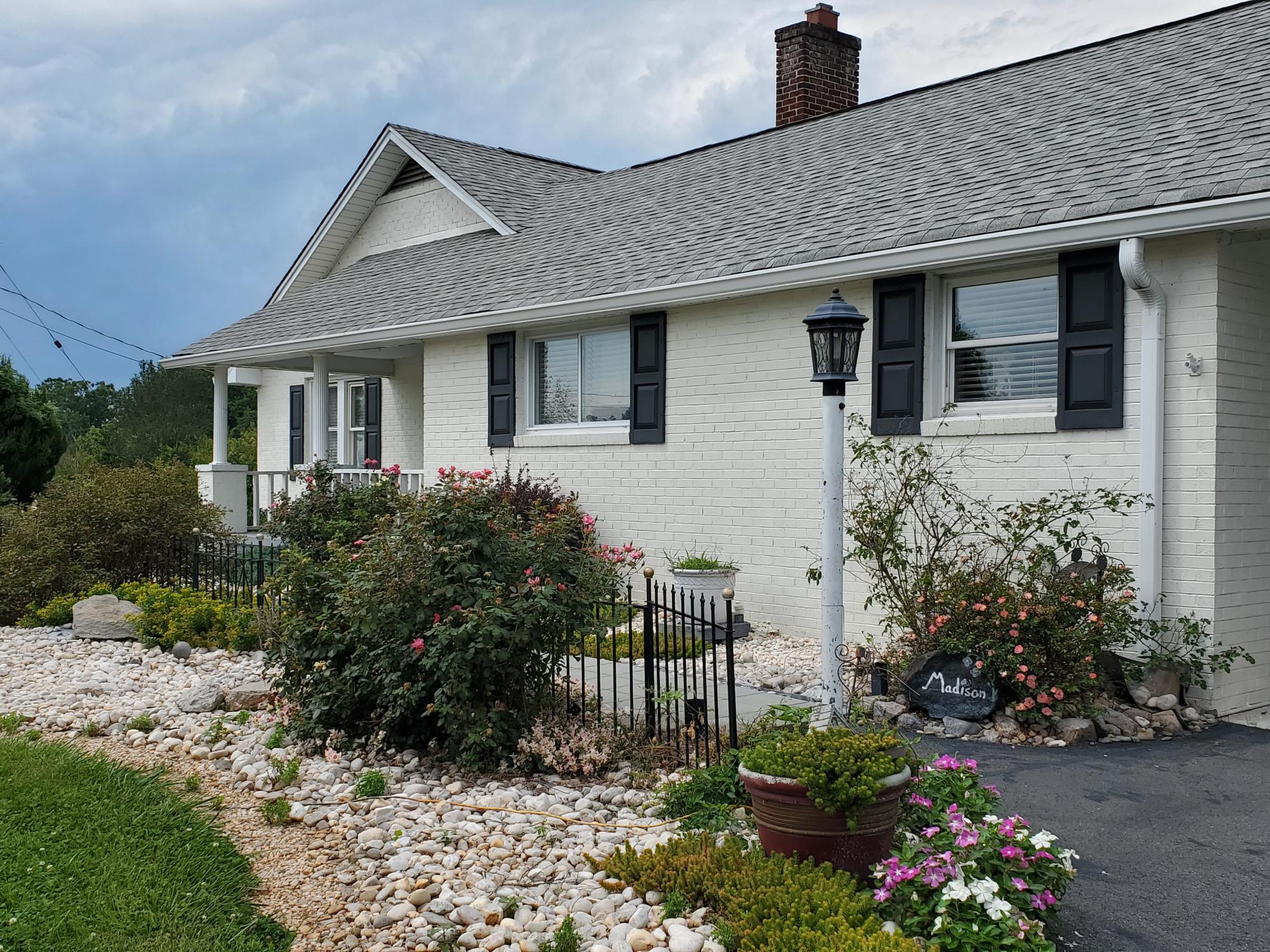 Greenery in front of a beige home with a gray roof