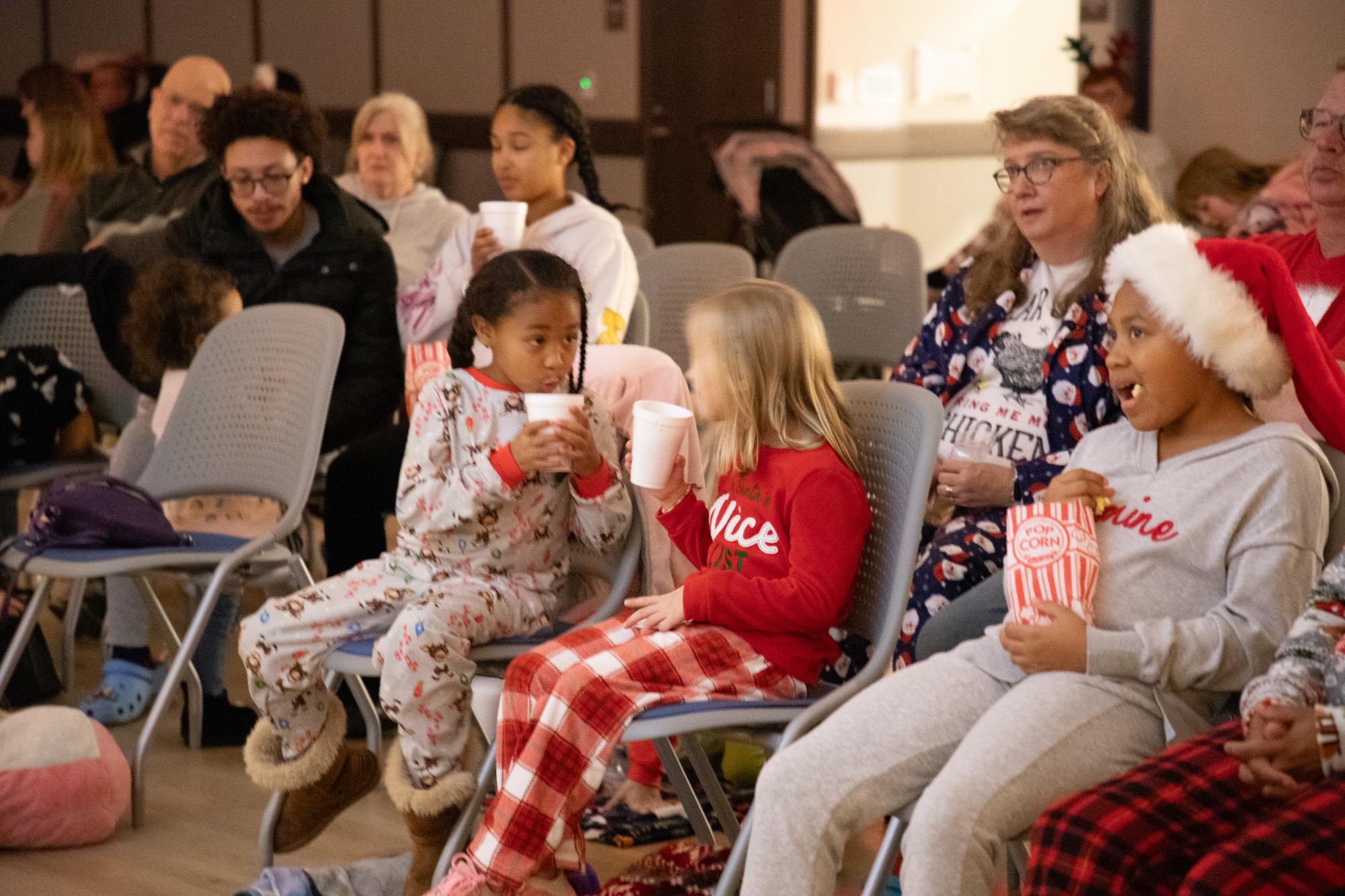 Two girls cool their hot chocolate down at the holiday movie night in Lewisville.