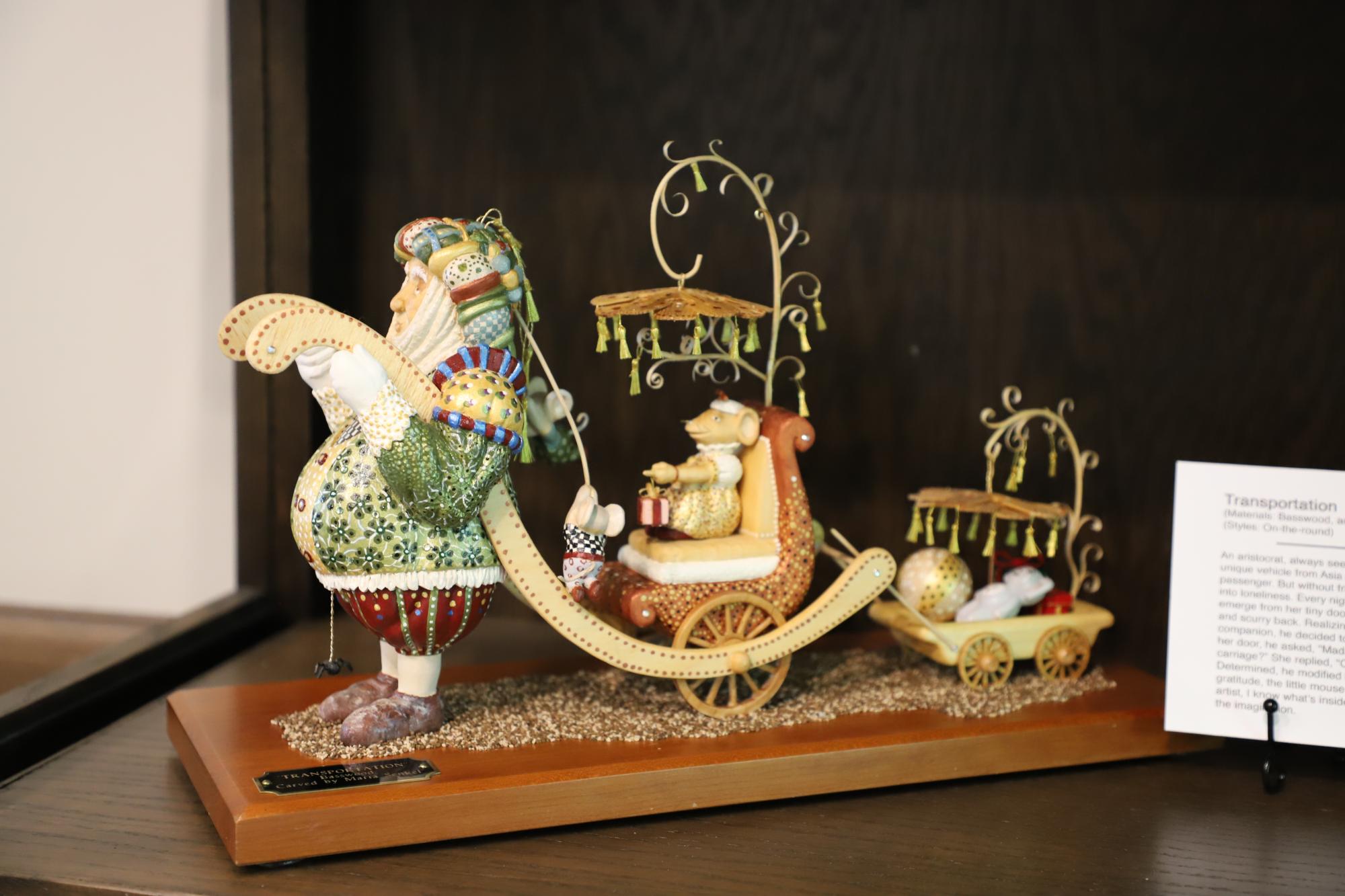 A wooden sculpture of a man pulling a whimsical carriage
